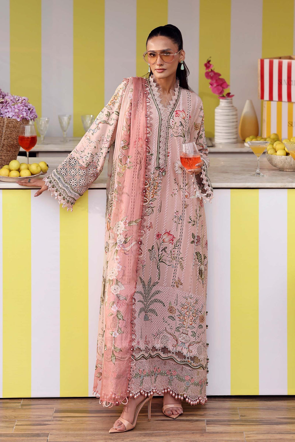 Woman in a floral dress standing in a kitchen with yellow and white striped walls.