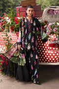 Woman in a floral outfit standing in front of a vintage car with floral decorations.