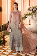 A woman models a traditional South Asian salwar kameez outfit in a warm, elegant indoor setting. The outfit consists of a dusty rose pink embroidered kameez jacket and matching dupatta over a sage green salwar pants set.