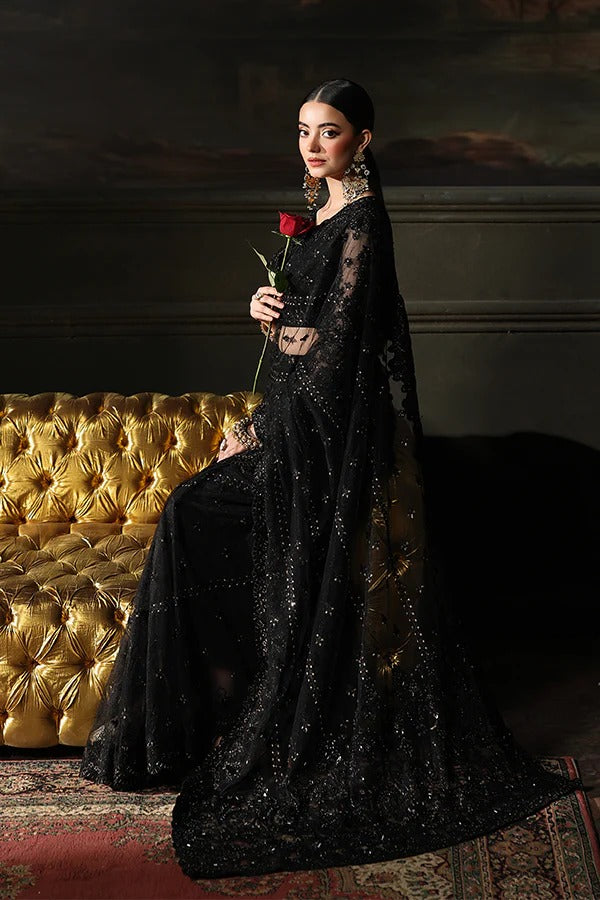 Woman in a black evening gown holding a red rose against a dark background
