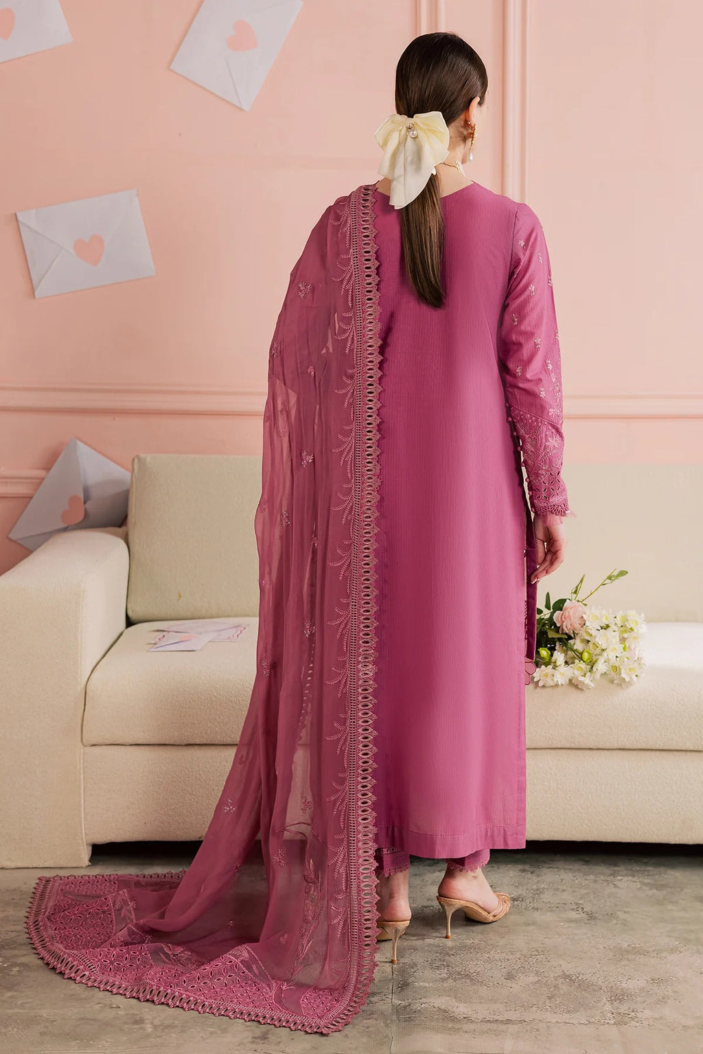 Woman in a pink traditional outfit with a matching dupatta in a living room setting.