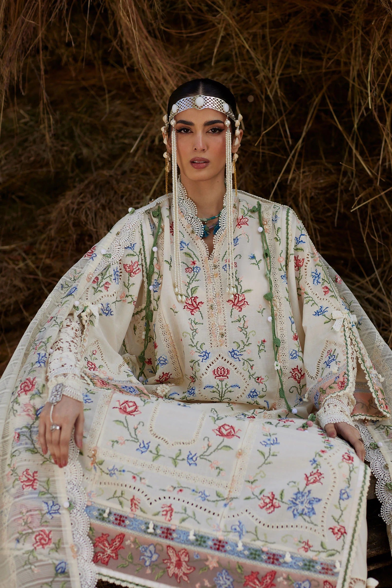 Woman in traditional embroidered outfit sitting against a natural background
