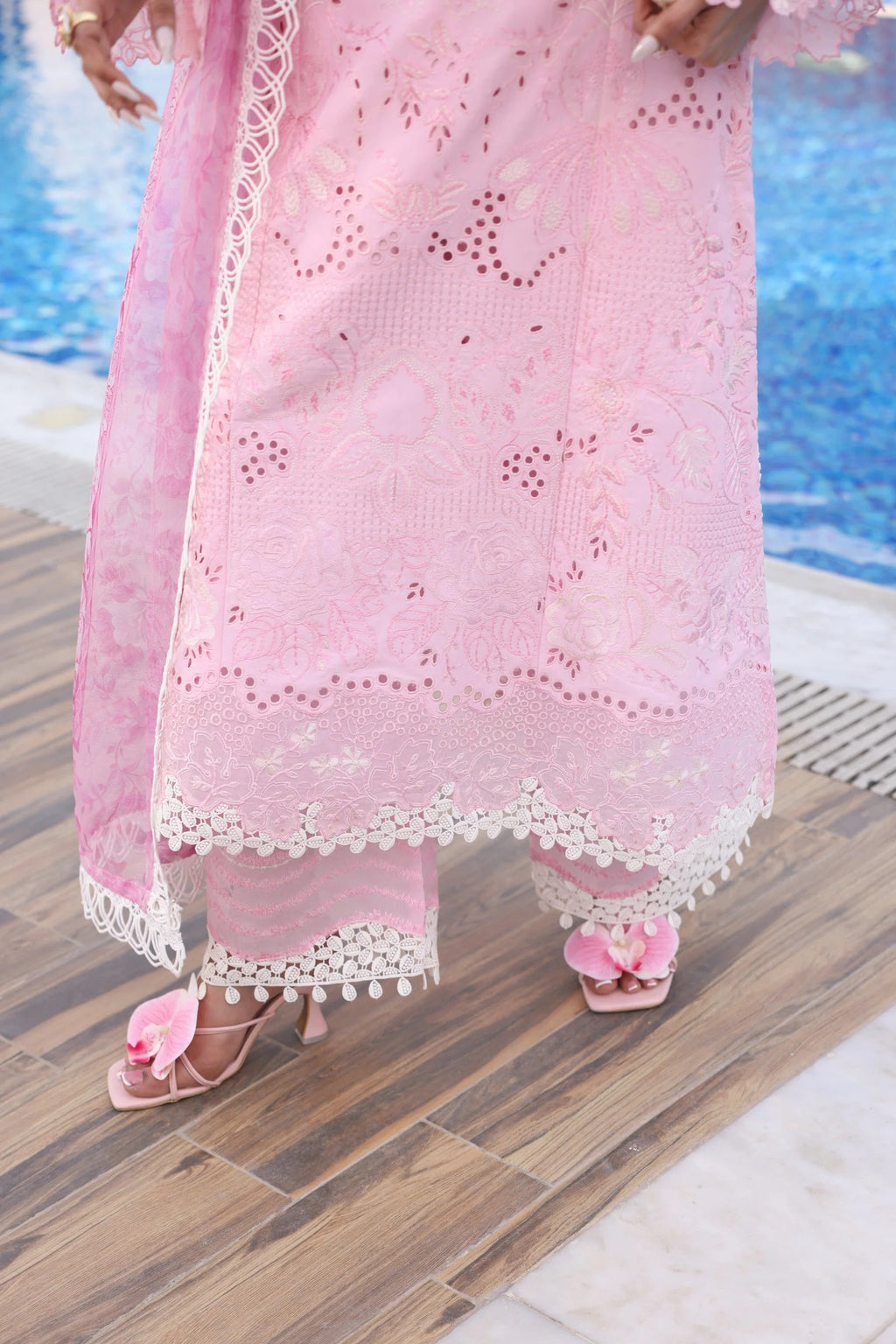Person wearing a pink lace outfit by a poolside