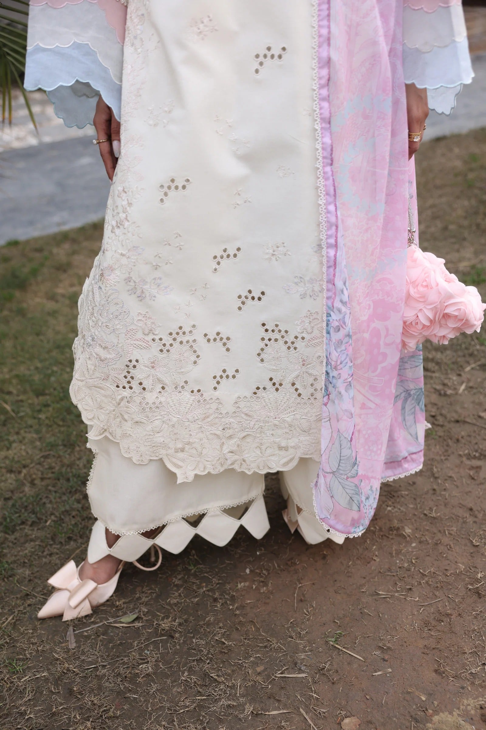 White lace dress with pink floral details on a natural background