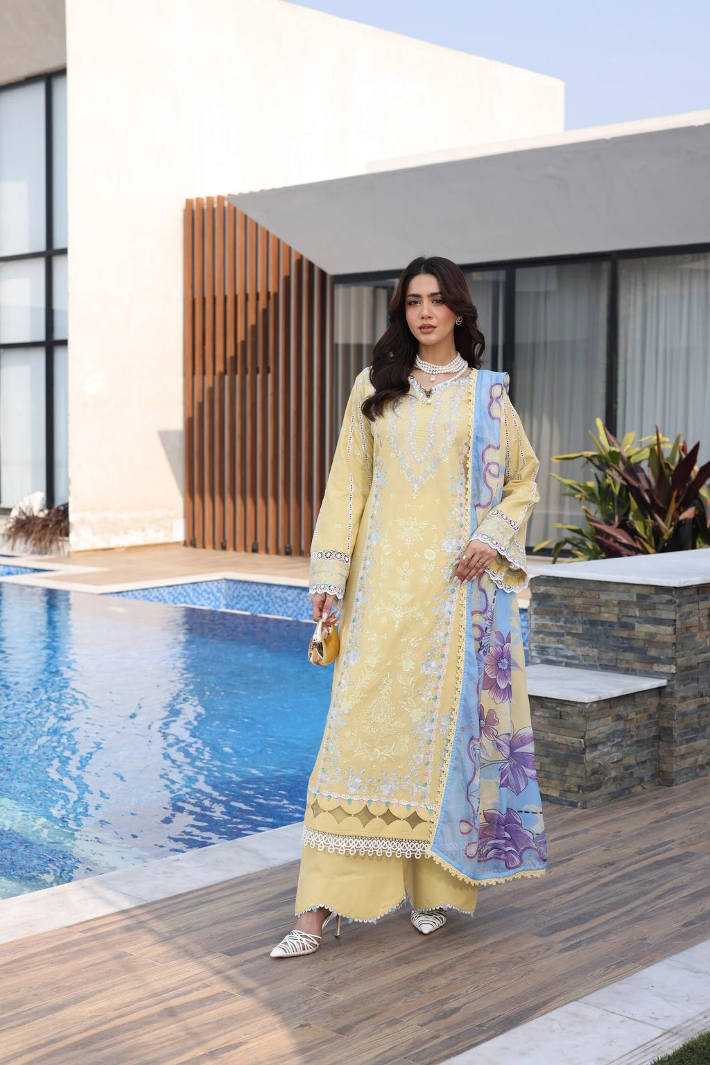 Woman in a yellow traditional outfit standing by a poolside.