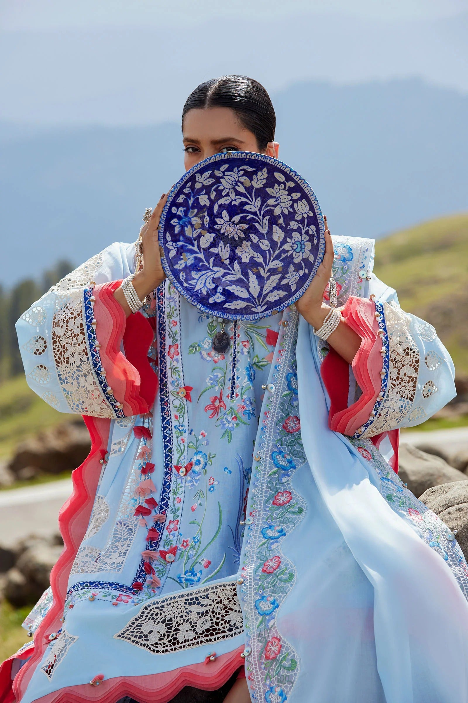 Woman holding a blue embroidered plate with a scenic background