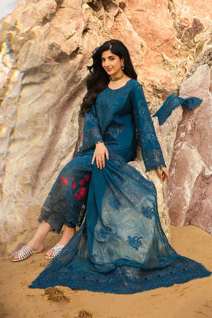 Woman in a blue traditional outfit standing against rocky beach background