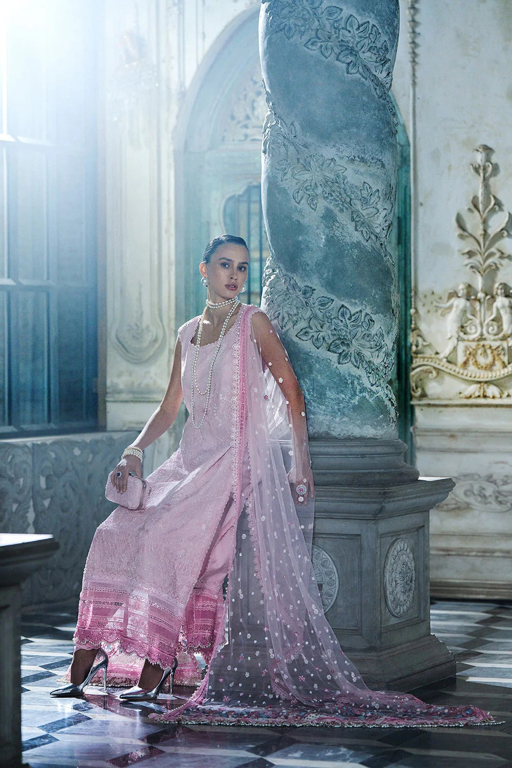 Woman in a pink saree standing in an elegant interior setting