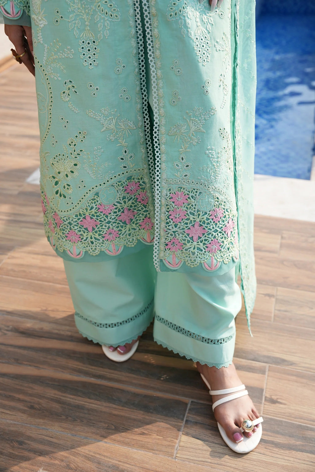 Person wearing a light blue embroidered outfit on a wooden floor.