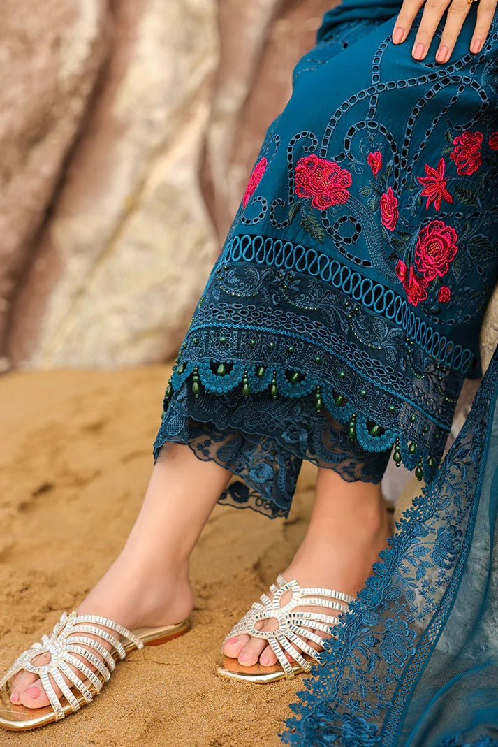 Person wearing blue embroidered pants and sandals on a sandy surface