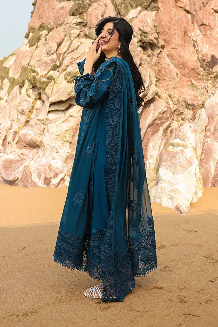 Woman in a blue dress standing on a rocky beach