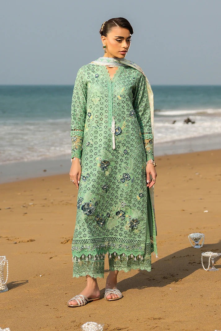 Woman in a green patterned dress standing on a beach with ocean in the background