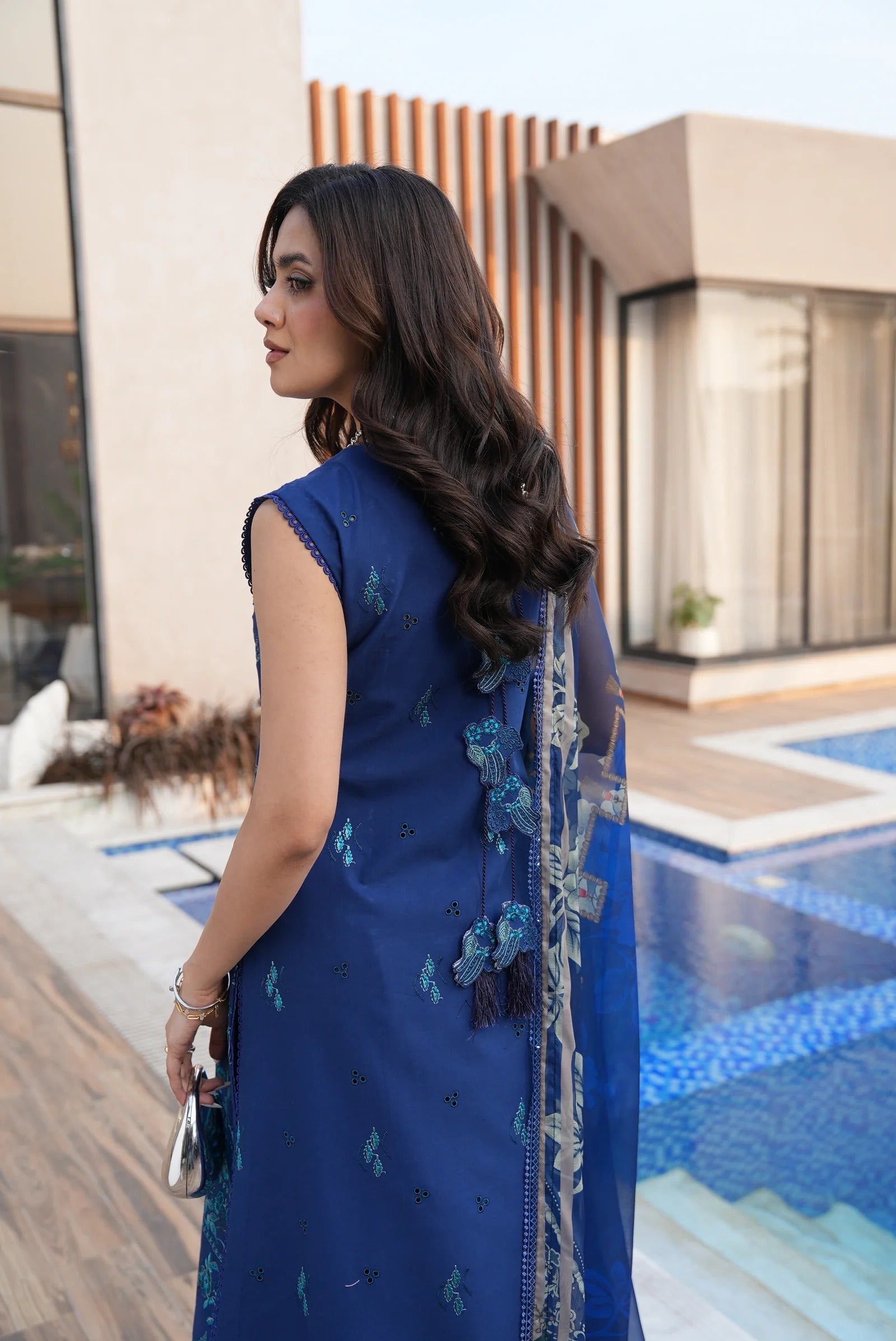 Woman in a blue saree standing by a poolside