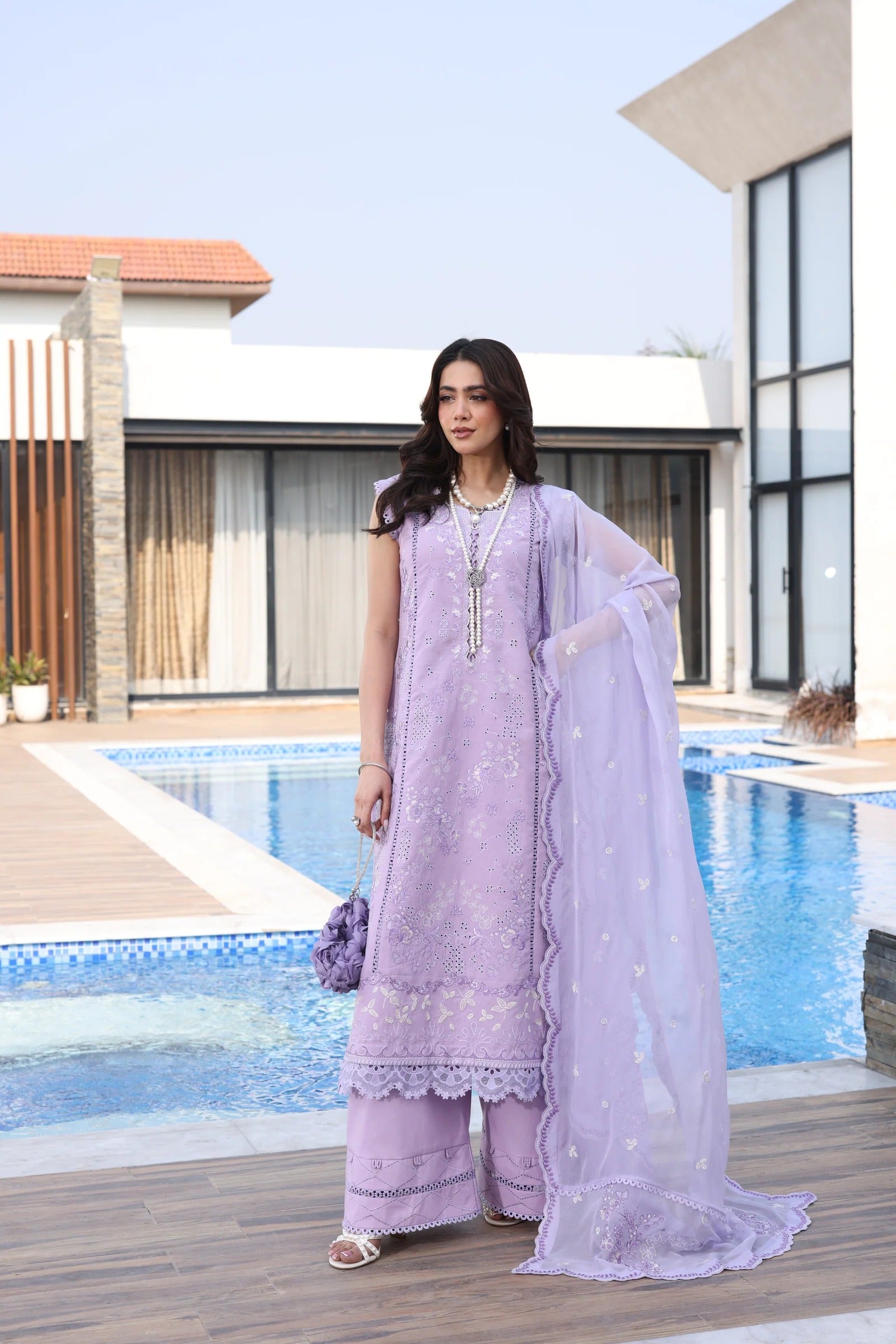 Woman in a lavender traditional outfit standing by a poolside.