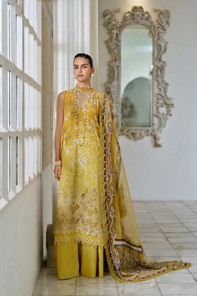 Woman in a yellow embroidered traditional outfit standing in a room with a decorative mirror.