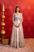 Woman in an elegant dress standing against a red wall with decorative elements.