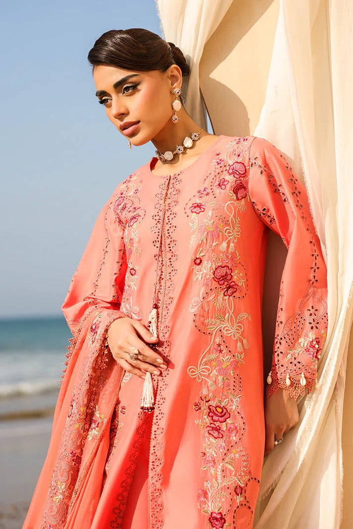 Woman in a pink embroidered outfit standing by a curtain with a beach in the background