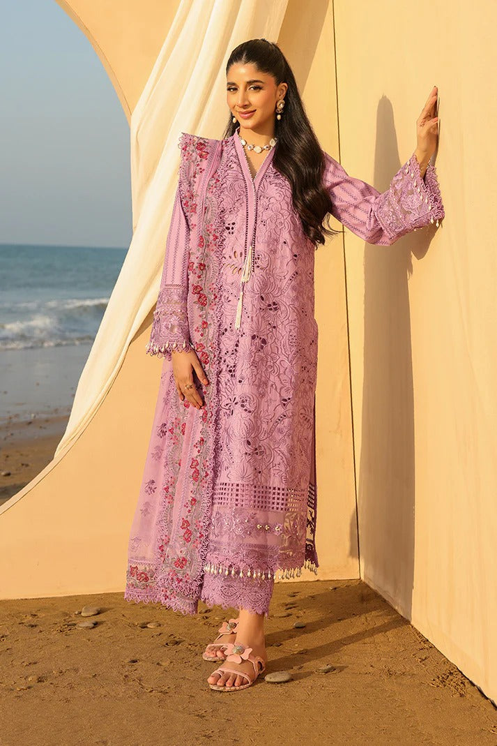 Woman in a pink embroidered outfit standing by a beige tent with ocean view
