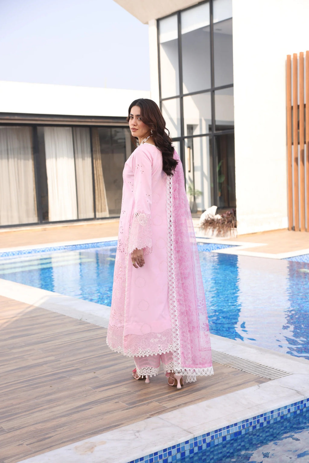 Woman in a pink traditional outfit standing by a poolside.
