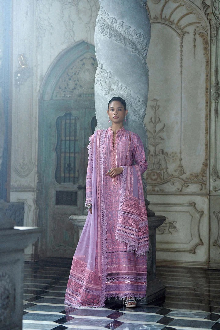 Woman in a pink traditional outfit standing in an ornate room.