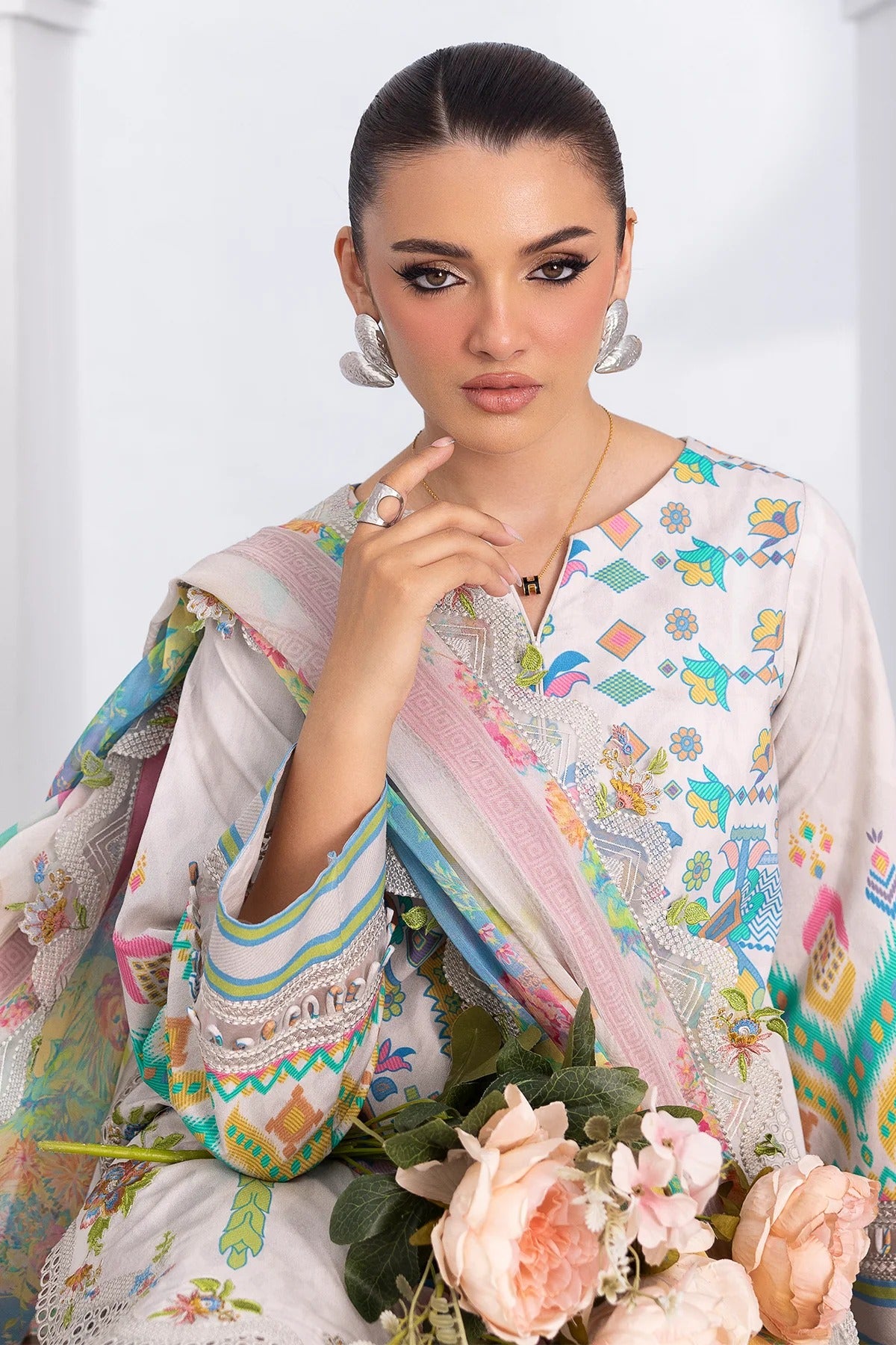 Woman wearing a colorful traditional outfit with floral decorations and jewelry.