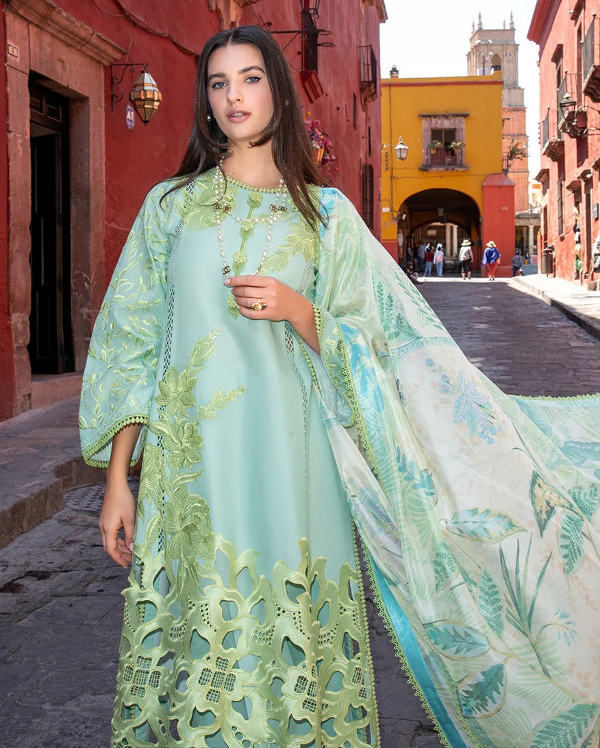 Woman in a light green embroidered dress standing on a street with colorful buildings.