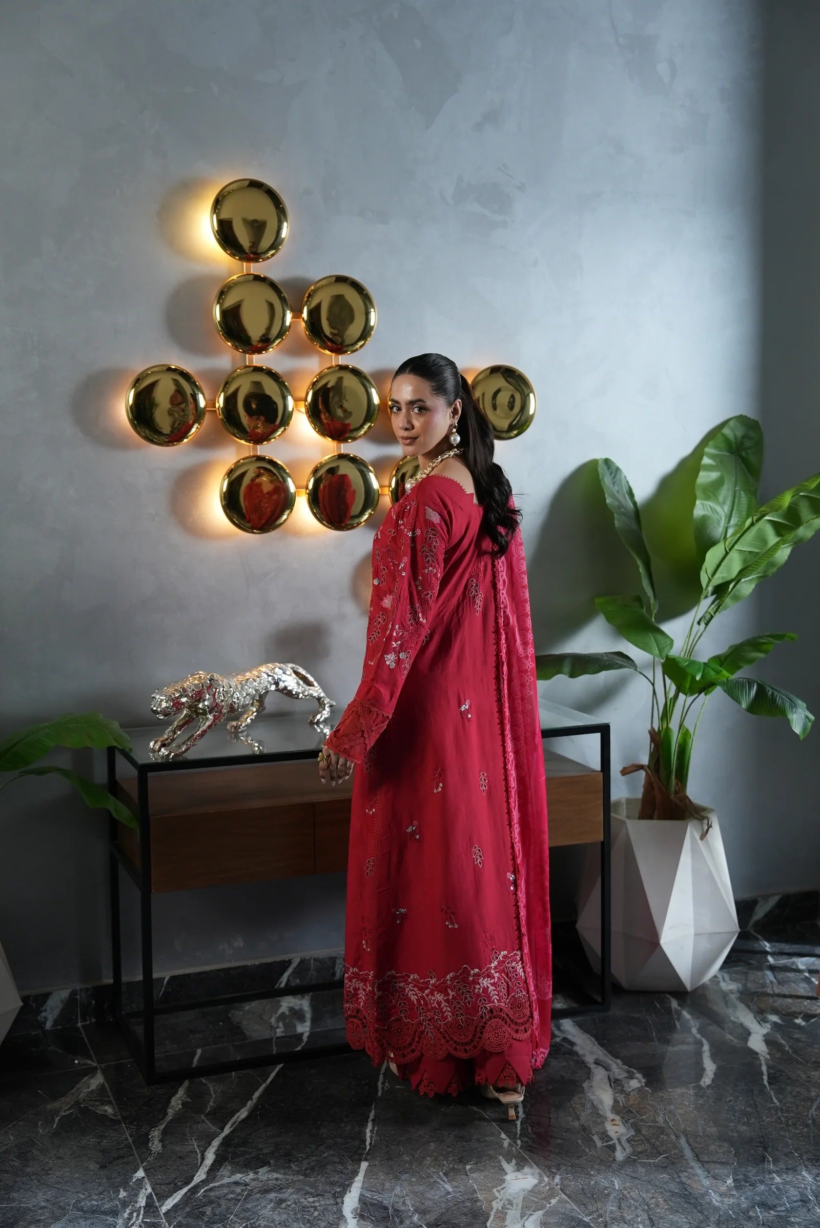 Woman in a red dress standing in a stylish room with decorative elements.