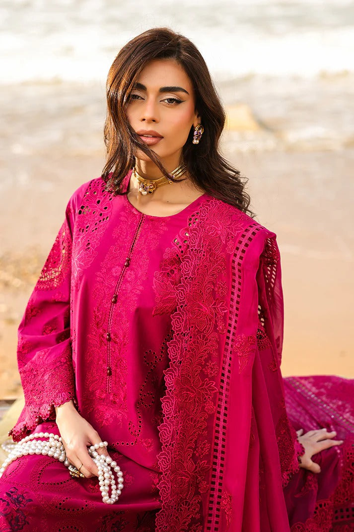 Woman in a bright pink traditional outfit with intricate designs against a blurred natural background