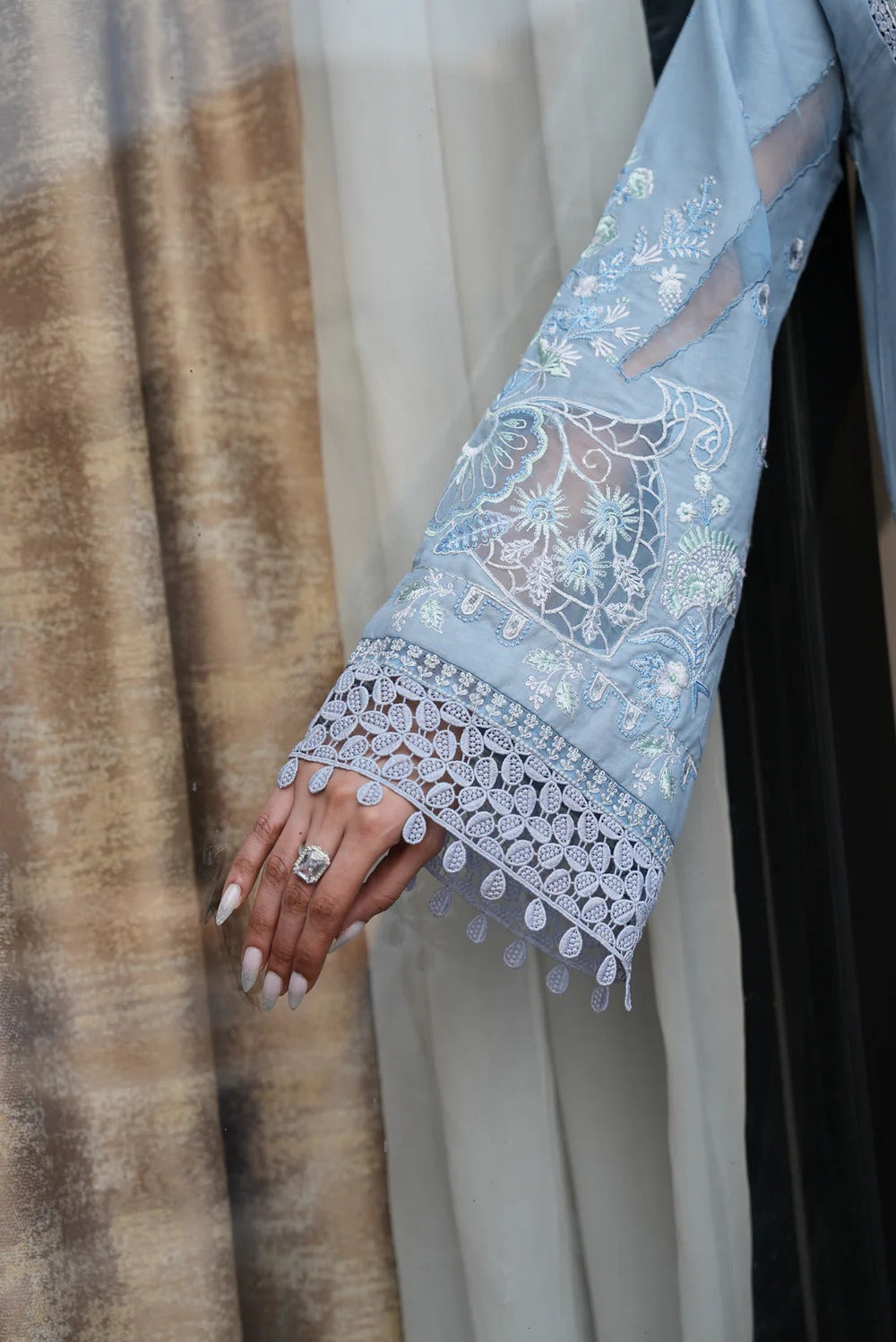 Light blue embroidered garment with lace details on a neutral background