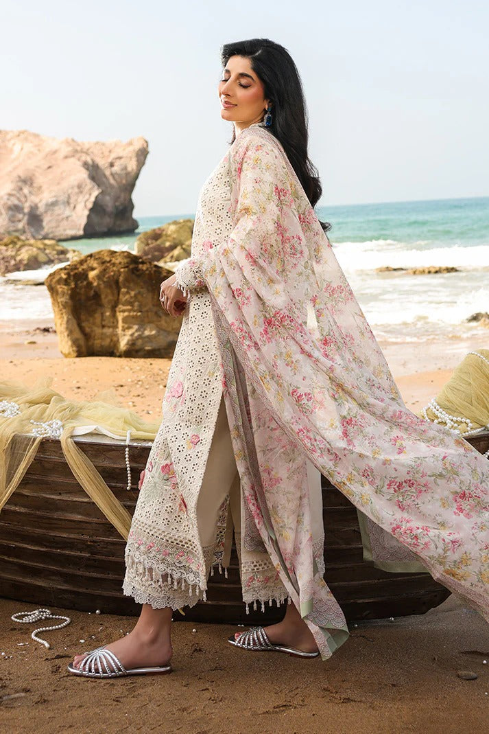 Woman in a floral dress standing on a beach with ocean and rocks in the background