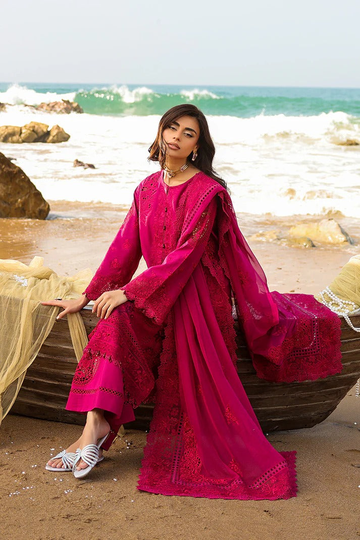 Woman in a pink traditional outfit sitting on a boat by the ocean.