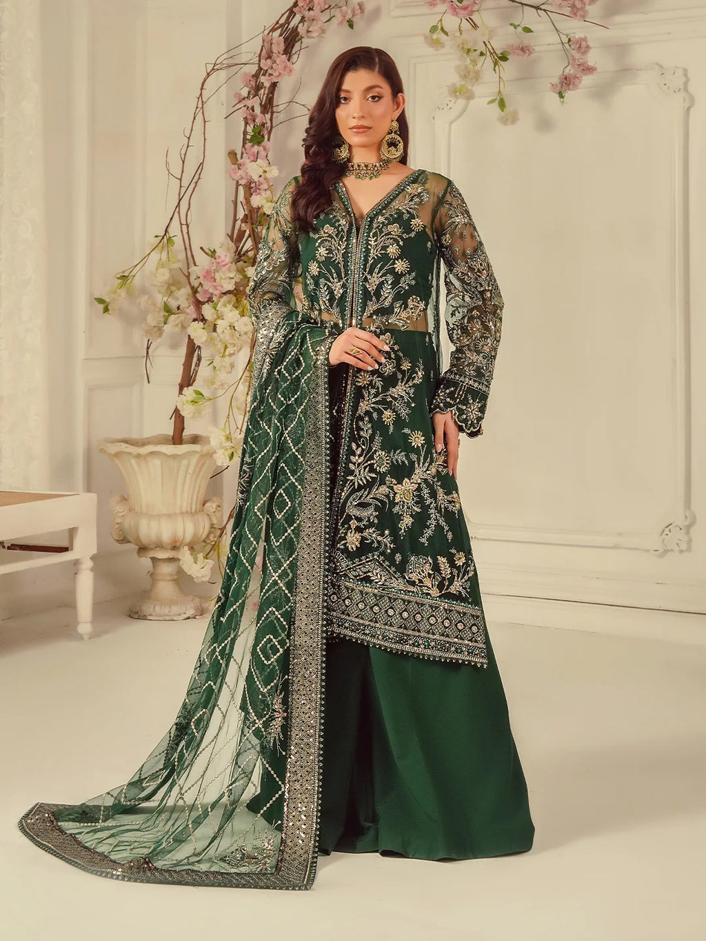 Woman wearing a green embroidered traditional outfit with a white background