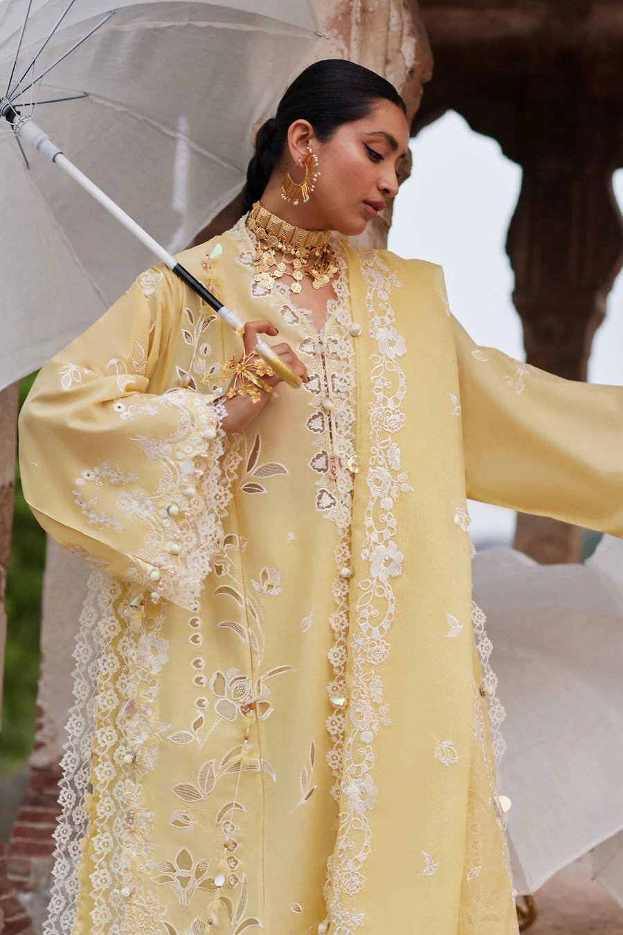 Woman in a yellow embroidered outfit holding an umbrella with an elephant in the background