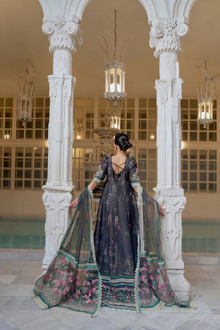 Woman in a dark floral dress standing in an elegant interior setting with white columns and chandeliers.