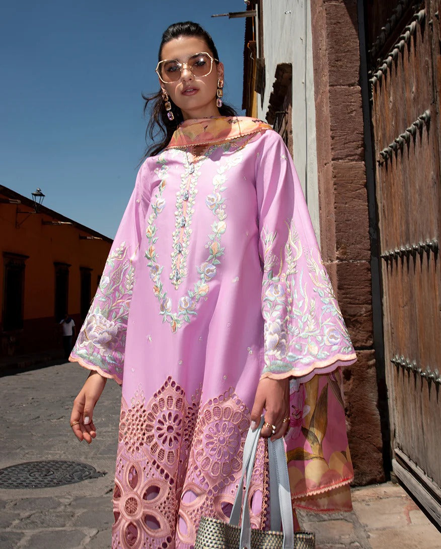 Woman in a pink embroidered outfit standing in front of a wooden door.