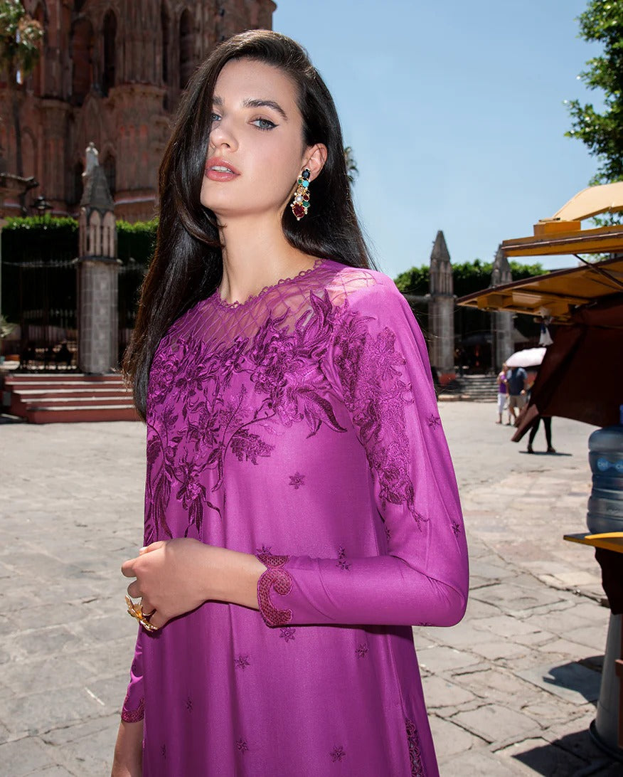 Woman wearing a purple embroidered dress in an outdoor setting with historical architecture.