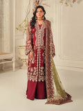 Woman wearing a red and gold embroidered traditional outfit with a matching dupatta in a decorated room.