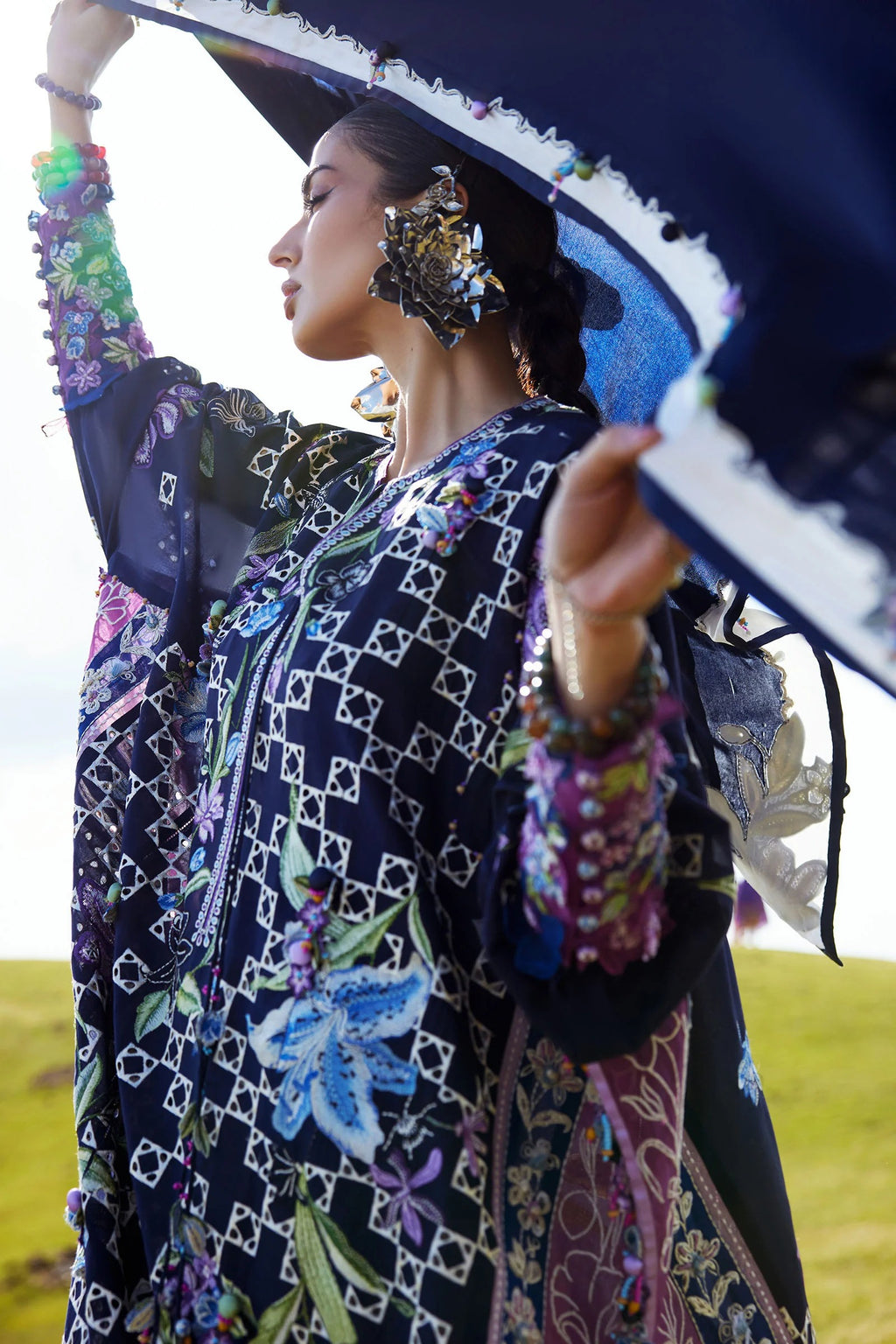 Woman wearing a colorful embroidered outfit with a large hat in an outdoor setting