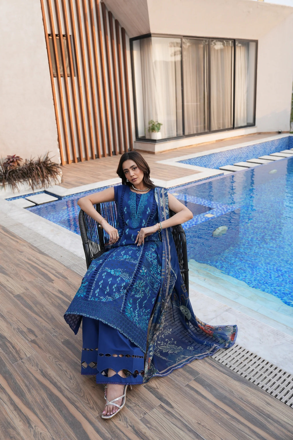 Woman in a blue dress sitting by a poolside