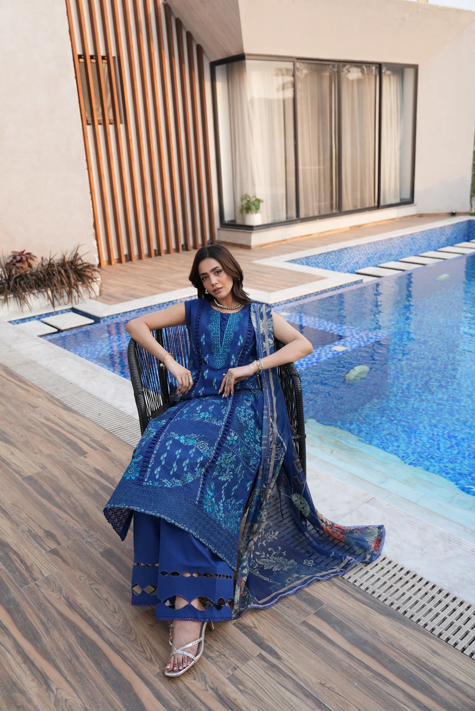 Woman in a blue dress sitting by a poolside