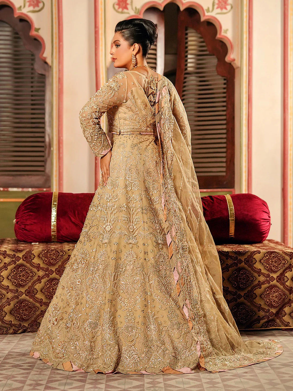Woman in a traditional embroidered outfit standing in an ornate room.