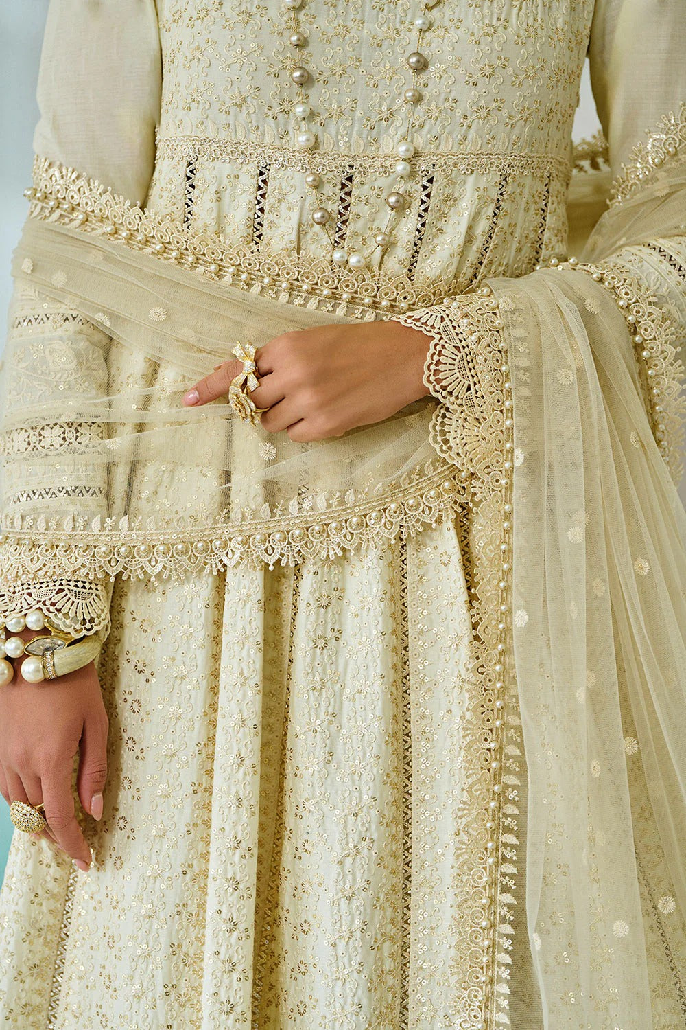 Close-up of a cream-colored embroidered traditional outfit with intricate patterns.