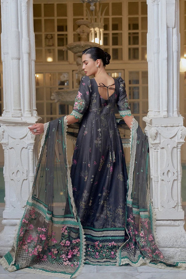 Woman in a dark blue embroidered saree with floral patterns in an elegant indoor setting.