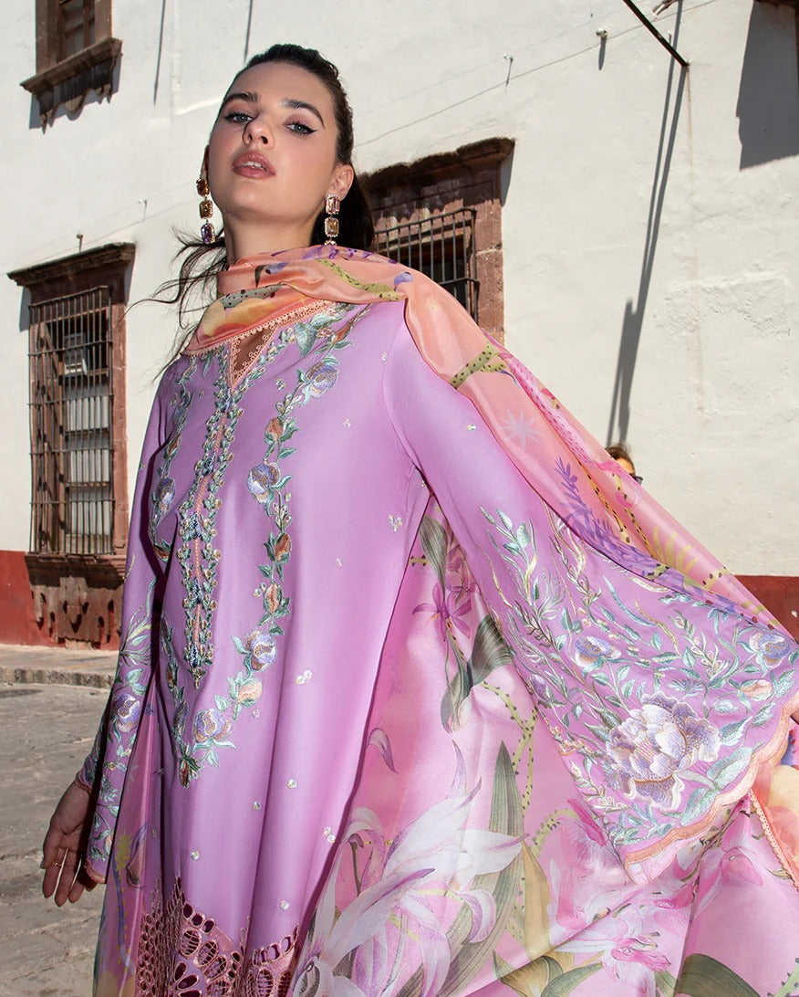 Woman wearing a vibrant, floral-patterned outfit with a pink dupatta in an outdoor setting.