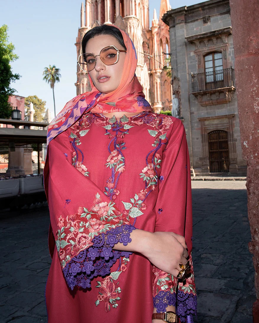 Woman wearing a vibrant red and floral embroidered dress with sunglasses, standing in front of a historic building.