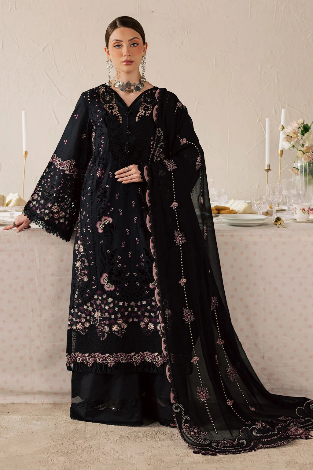 Woman in a black embroidered traditional outfit standing in a formal setting.