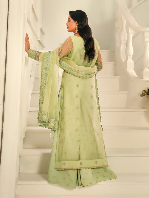Woman in a light green traditional outfit standing on a white staircase.