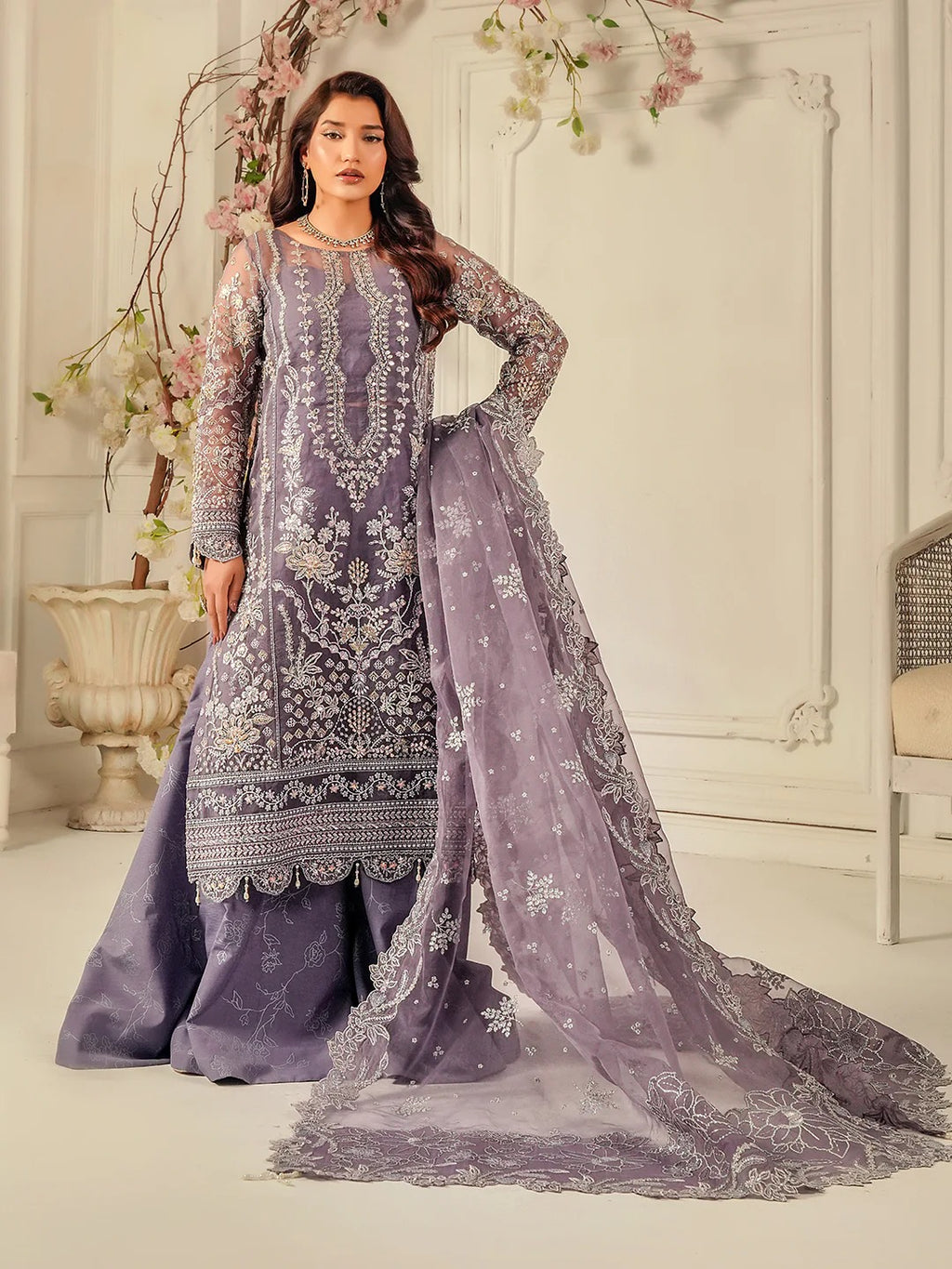 Woman in a purple embroidered traditional outfit with a white background