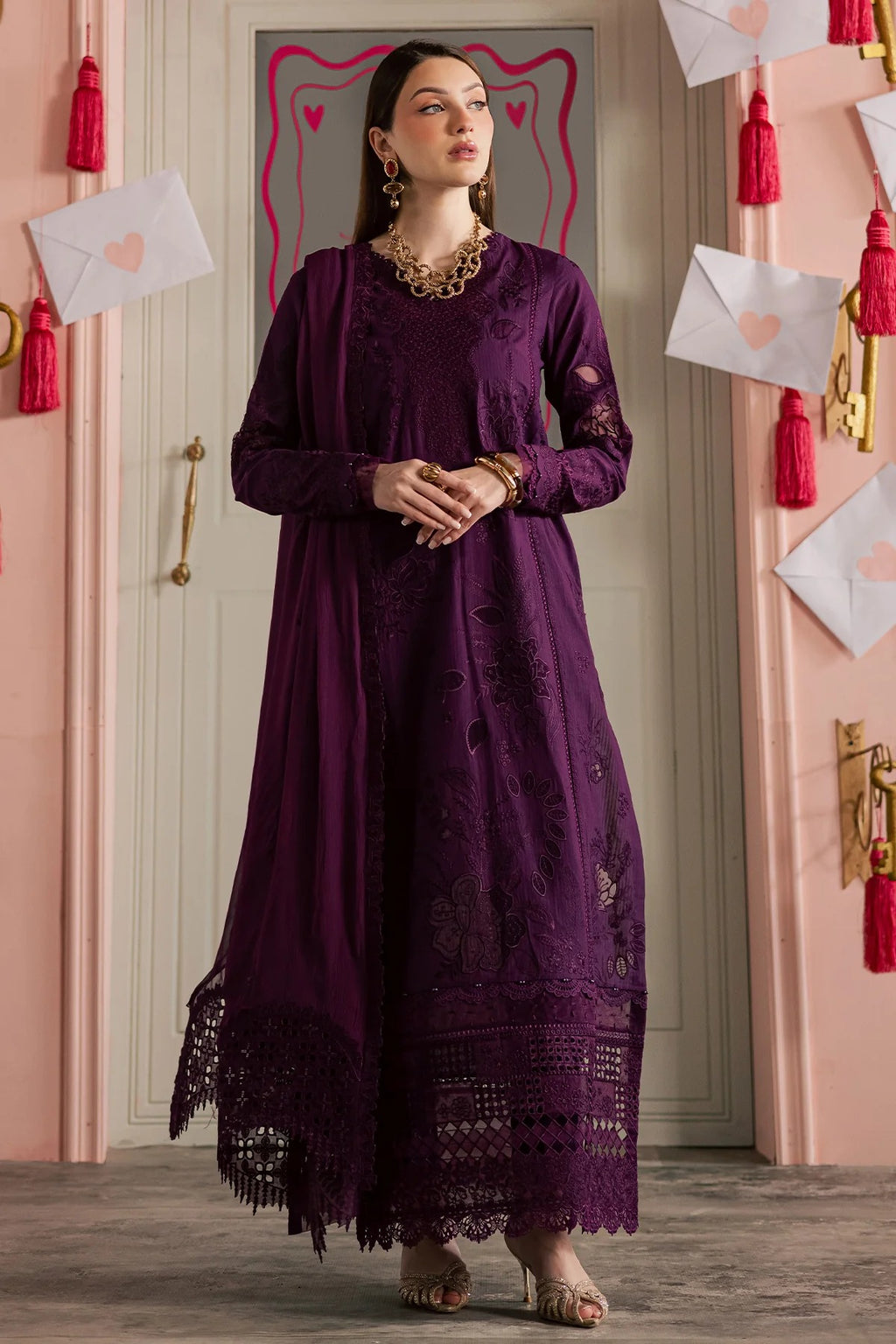 Woman in a long purple dress standing in a room with decorative elements.