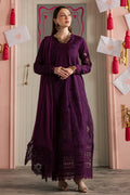 Woman in a long purple dress standing in a room with decorative elements.